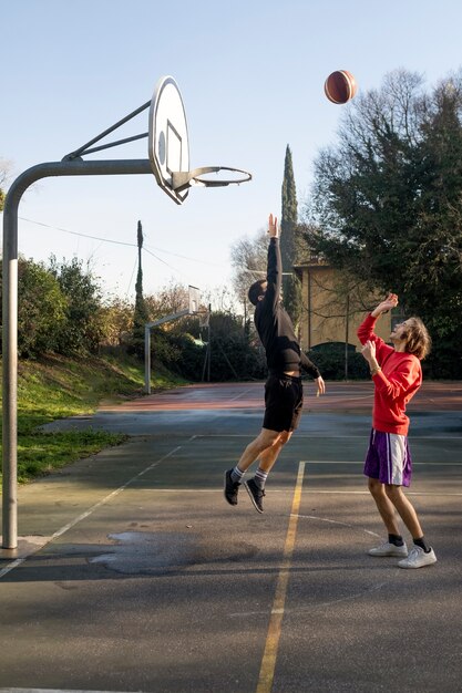 Amis d'âge moyen s'amusant ensemble en jouant au basket