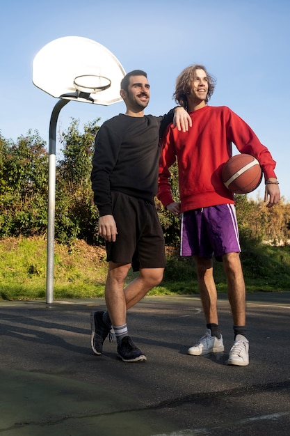 Amis d'âge moyen s'amusant ensemble en jouant au basket