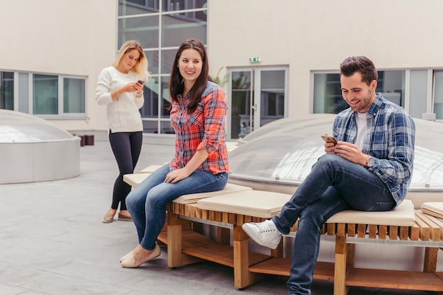 Amis à l&#39;aide de téléphones sur le banc