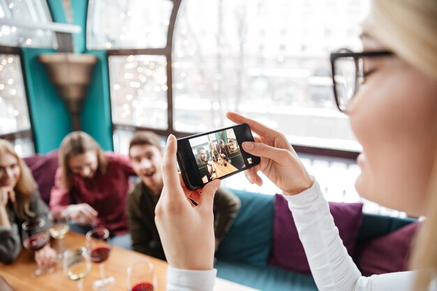 Amis attrayants assis dans un café et faire des photos par téléphone.
