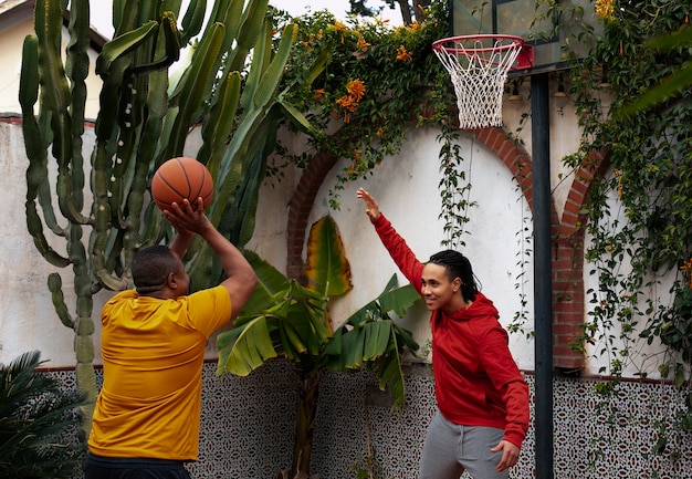 Photo gratuite amis à coup moyen jouant au basket à l'extérieur