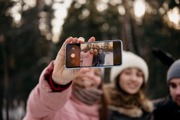 Amis ensemble prenant selfie à l'extérieur en hiver