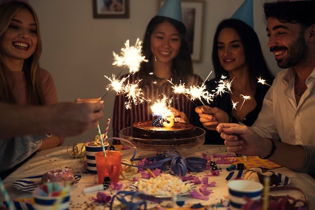 Photo gratuite amis avec des feux de bengale à la fête d'anniversaire