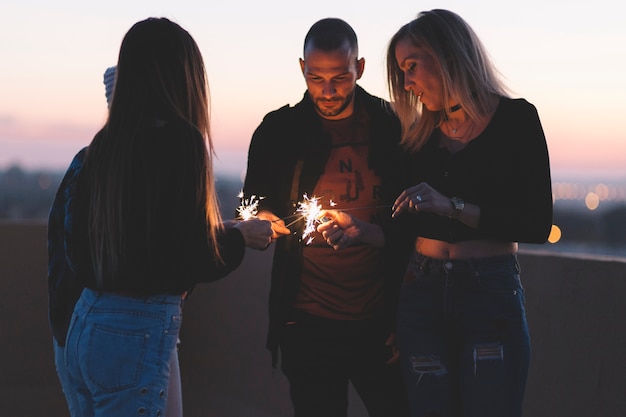 Photo gratuite amis avec des feux de bengale sur le toit