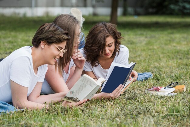 Amis de filles attrayantes lisant ensemble en été