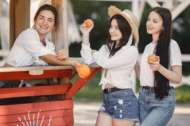 Amis avec des fruits. Fille au chapeau. Femme dans un t-shirt blanc.