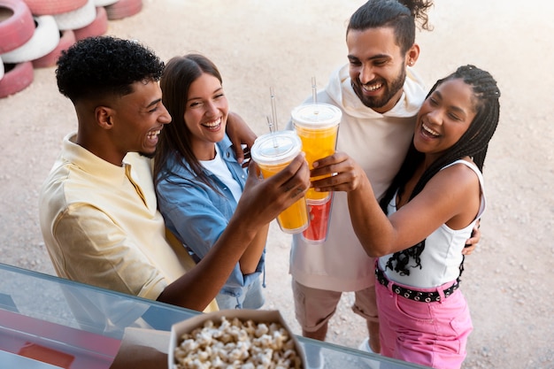 Photo gratuite amis heureux à angle élevé tintant des tasses