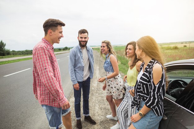 Amis heureux, debout, dehors, voiture, apprécier, route