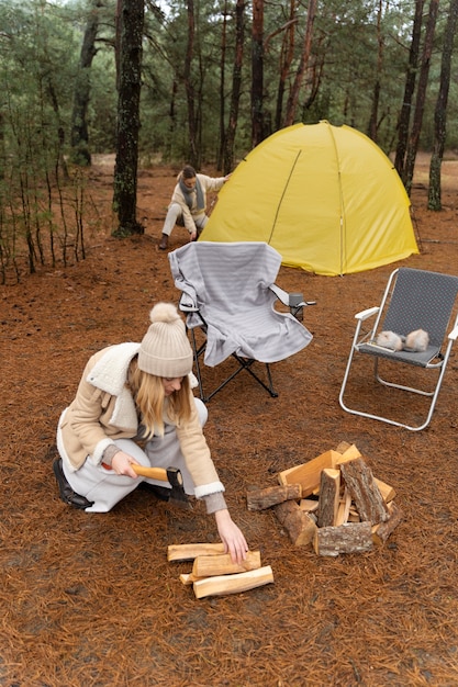 Amis installant une tente et coupant du bois pour un feu de joie