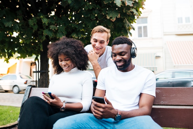 Photo gratuite amis interculturels assis sur un banc