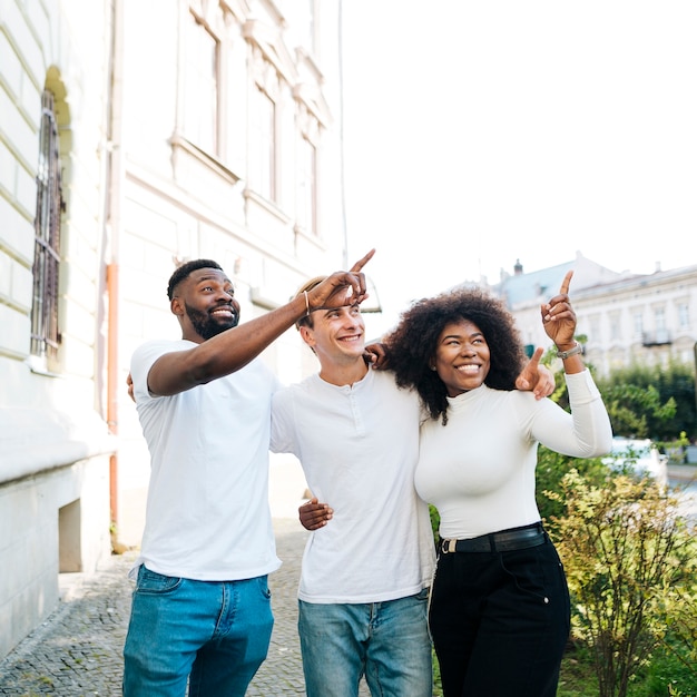 Amis interculturels s'embrassant et se montrant en même temps