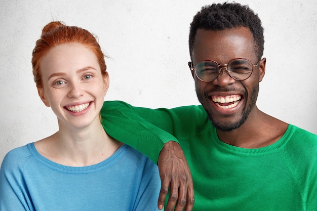 Photo gratuite des amis interraciaux, femmes et hommes, s'amusent ensemble: un homme à la peau sombre ravi se moque d'une bonne blague