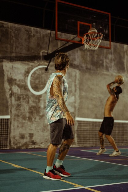 Des amis jouent au basket. Les jeunes hommes jouent au basket dans la rue.