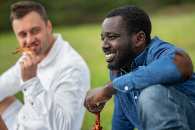 Photo gratuite amis masculins à l'extérieur manger barbecue