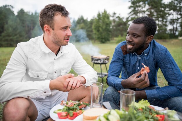 Amis masculins, manger un barbecue à l'extérieur