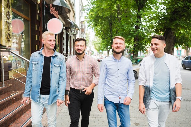 Amis masculins modernes marchant ensemble sur la rue de la ville