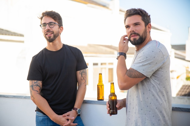 Amis masculins regardant à distance tout en buvant de la bière