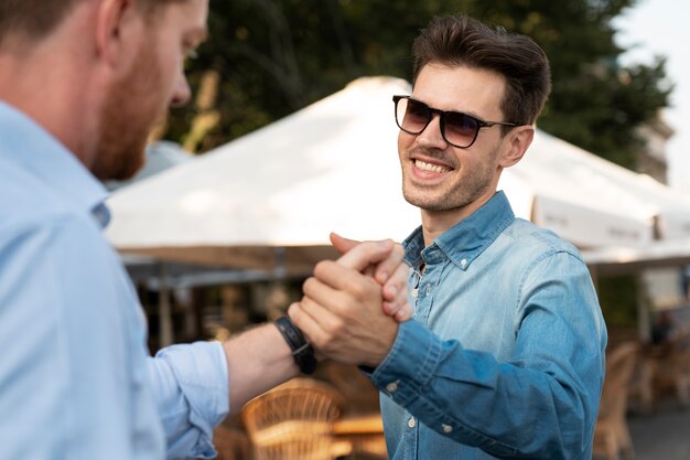 Amis masculins se serrant la main à l'extérieur