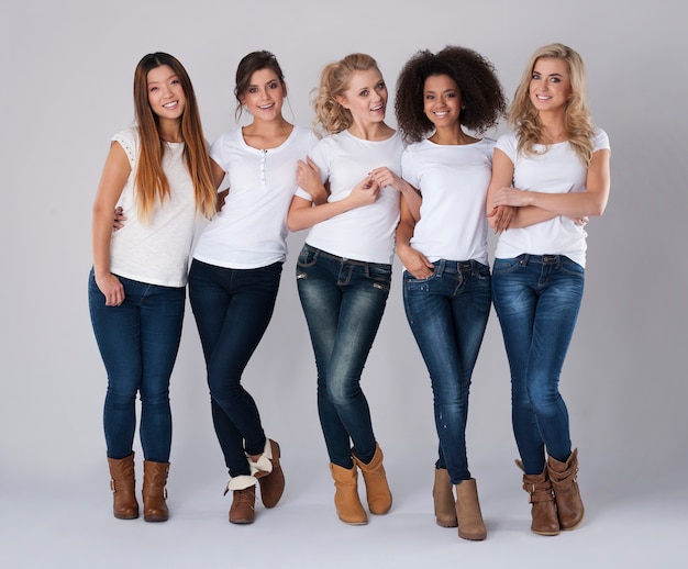 Amis multiethniques portant des jeans et des t-shirts blancs