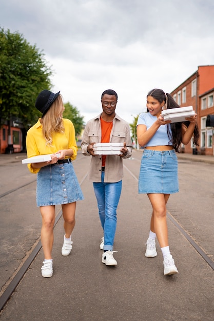 Photo gratuite amis avec pizza à l'extérieur plein coup