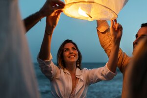 Photo gratuite amis à la plage lançant une lanterne pendant la nuit
