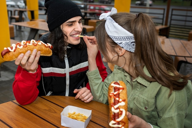 Amis de plan moyen mangeant de la restauration rapide d'une manière amusante