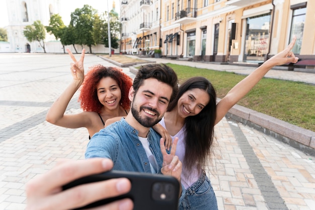Amis de plan moyen prenant des selfies avec un téléphone