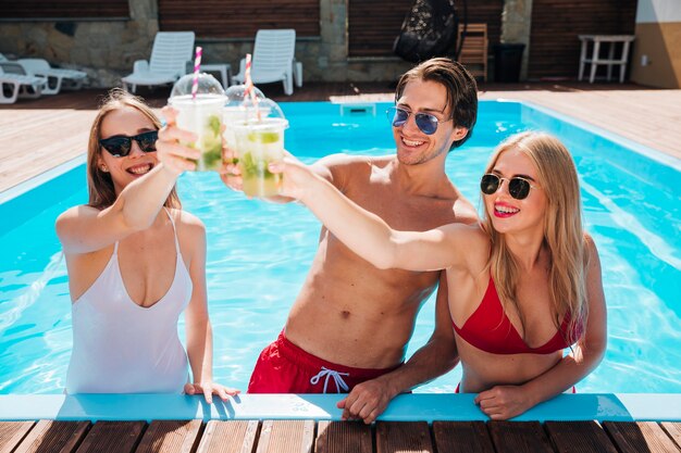 Amis portant un toast avec des cocktails dans la piscine