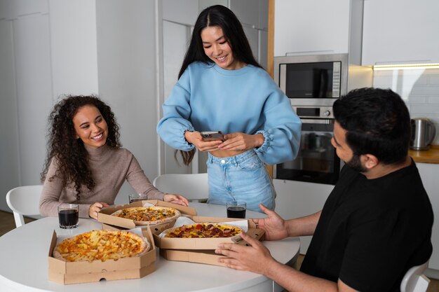 Amis prenant des photos en mangeant de la pizza à la maison