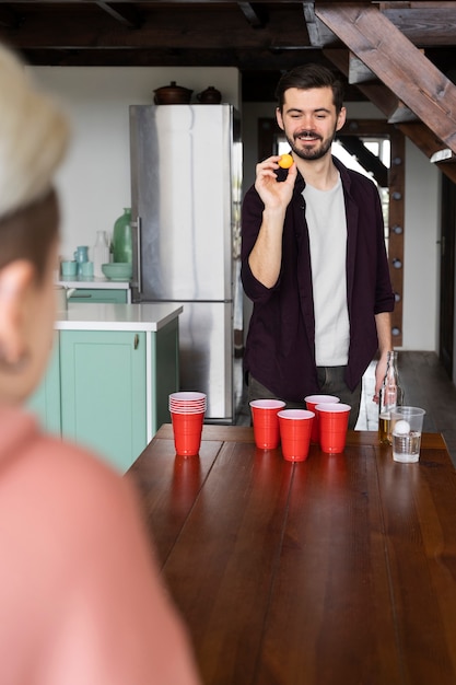 Photo gratuite amis profitant d'un jeu de bière-pong lors d'une fête en salle