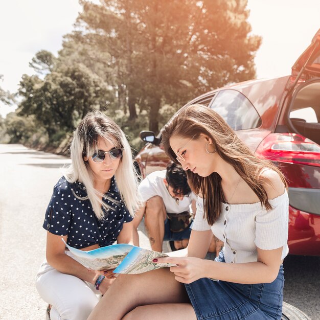 Amis en regardant la carte près de la voiture en panne