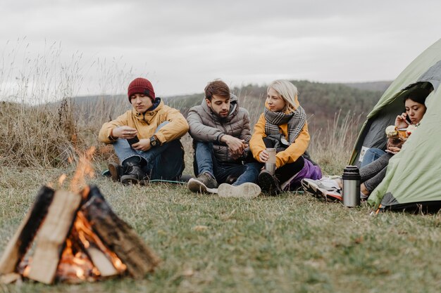 Des amis s'échauffent sur un feu de camp