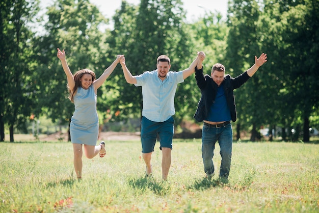 Amis satisfaits en train de courir et tenant les mains en l'air