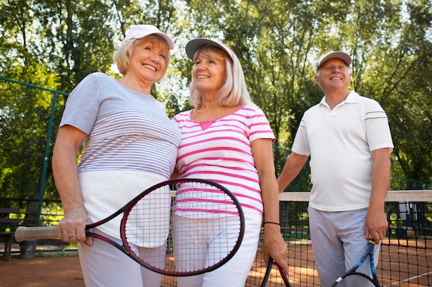 Amis seniors souriants de coup moyen avec raquette