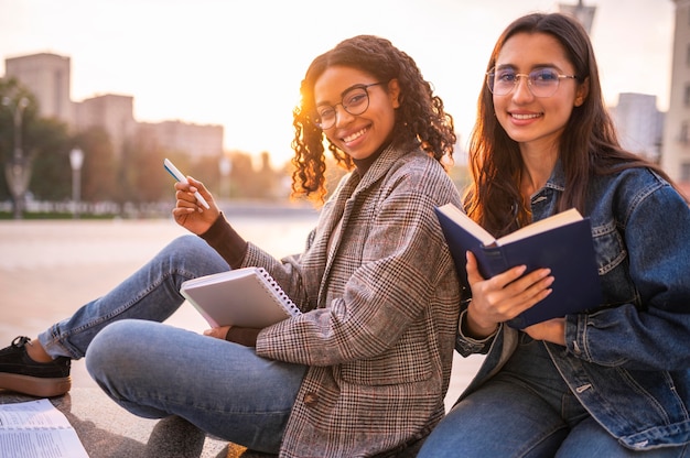 Photo gratuite amis smiley à faire leurs devoirs dans la ville