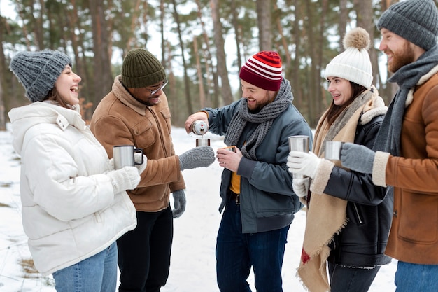 Amis souriants avec boissons chaudes plan moyen