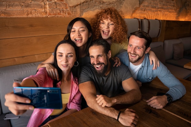 Amis souriants de plan moyen prenant des selfies