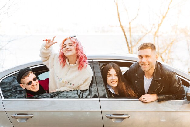 Amis souriants regardant par la fenêtre de la voiture