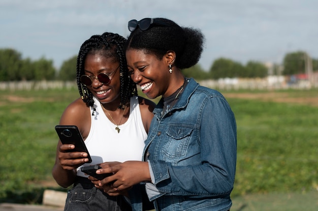 Amis souriants avec smartphone plan moyen