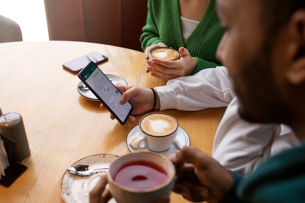 Amis souriants vue latérale avec smartphone