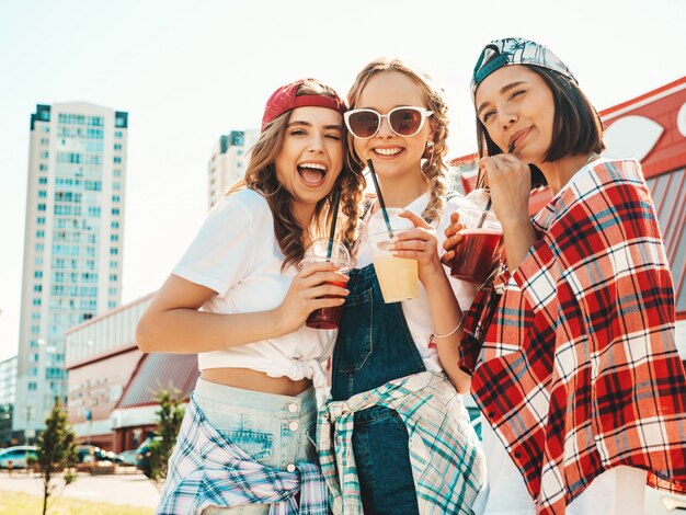 Amis tenant et boire un smoothie cocktail frais dans une tasse en plastique avec de la paille