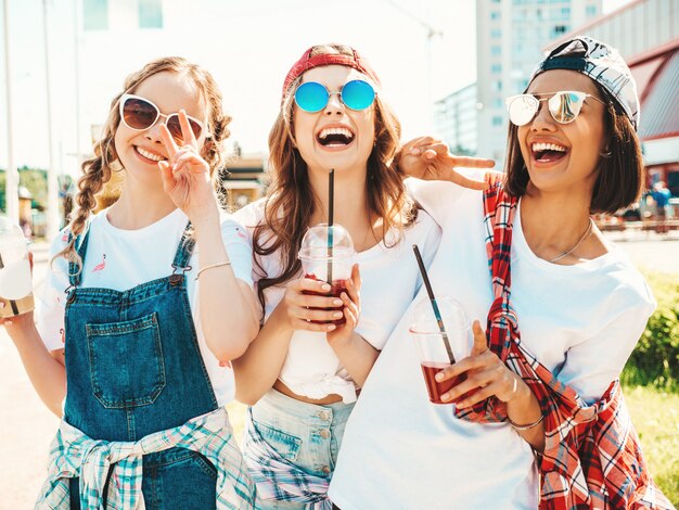 Amis tenant et boire un smoothie cocktail frais dans une tasse en plastique avec de la paille