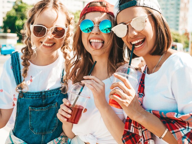 Amis tenant et boire un smoothie cocktail frais dans une tasse en plastique avec de la paille