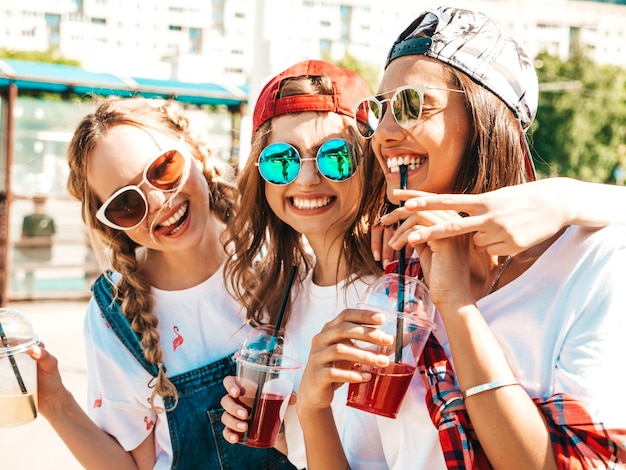 Amis tenant et boire un smoothie cocktail frais dans une tasse en plastique avec de la paille