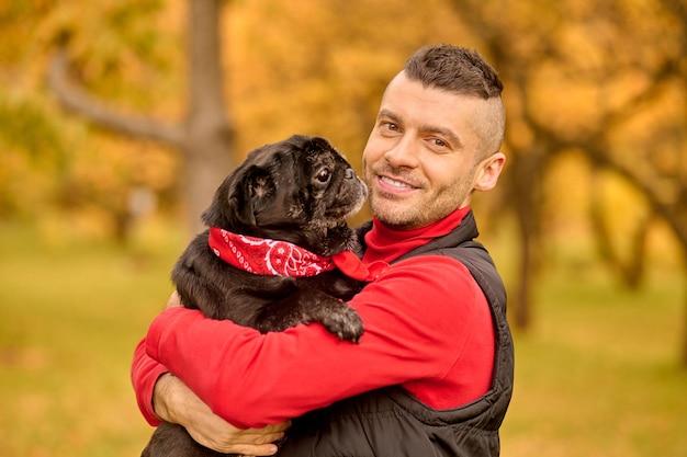 Photo gratuite amour. un homme debout dans le parc et serrant son chien dans ses bras