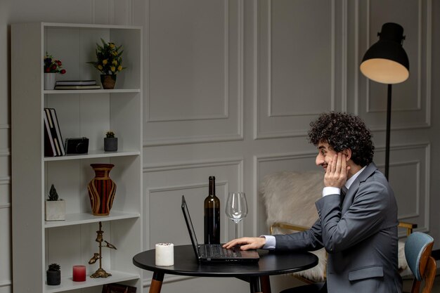 Amour virtuel beau mec mignon en costume avec du vin à une date d'ordinateur à distance avec la main sur le visage