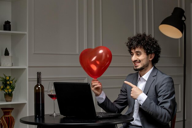 Amour virtuel beau mec mignon en costume avec du vin sur une date d'ordinateur à distance pointant vers un ballon