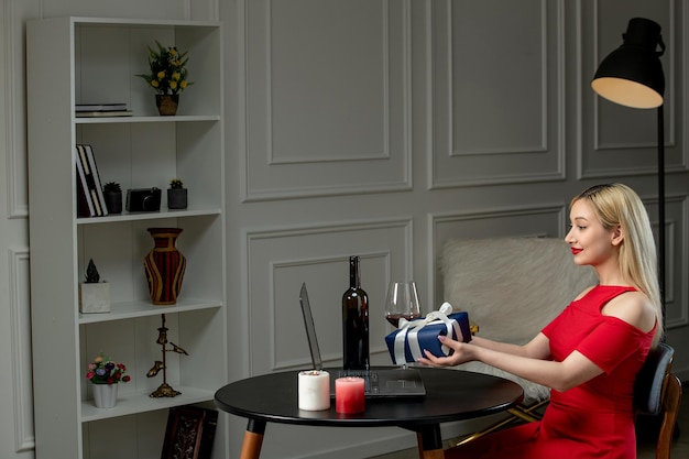 Amour Virtuel Jolie Fille Blonde En Robe Rouge à Distance Avec Du Vin Et Des Bougies Donnant Le Cadeau Photo Premium
