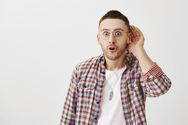 Amusé beau jeune homme avec des lunettes posant