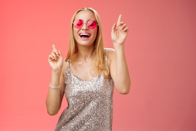 Amusée séduisante femme souriante dansant discothèque s'amusant à profiter d'une fête sauvage célébrant le b-jour portant des lunettes de soleil élégantes lève l'index souriant en chantant le long